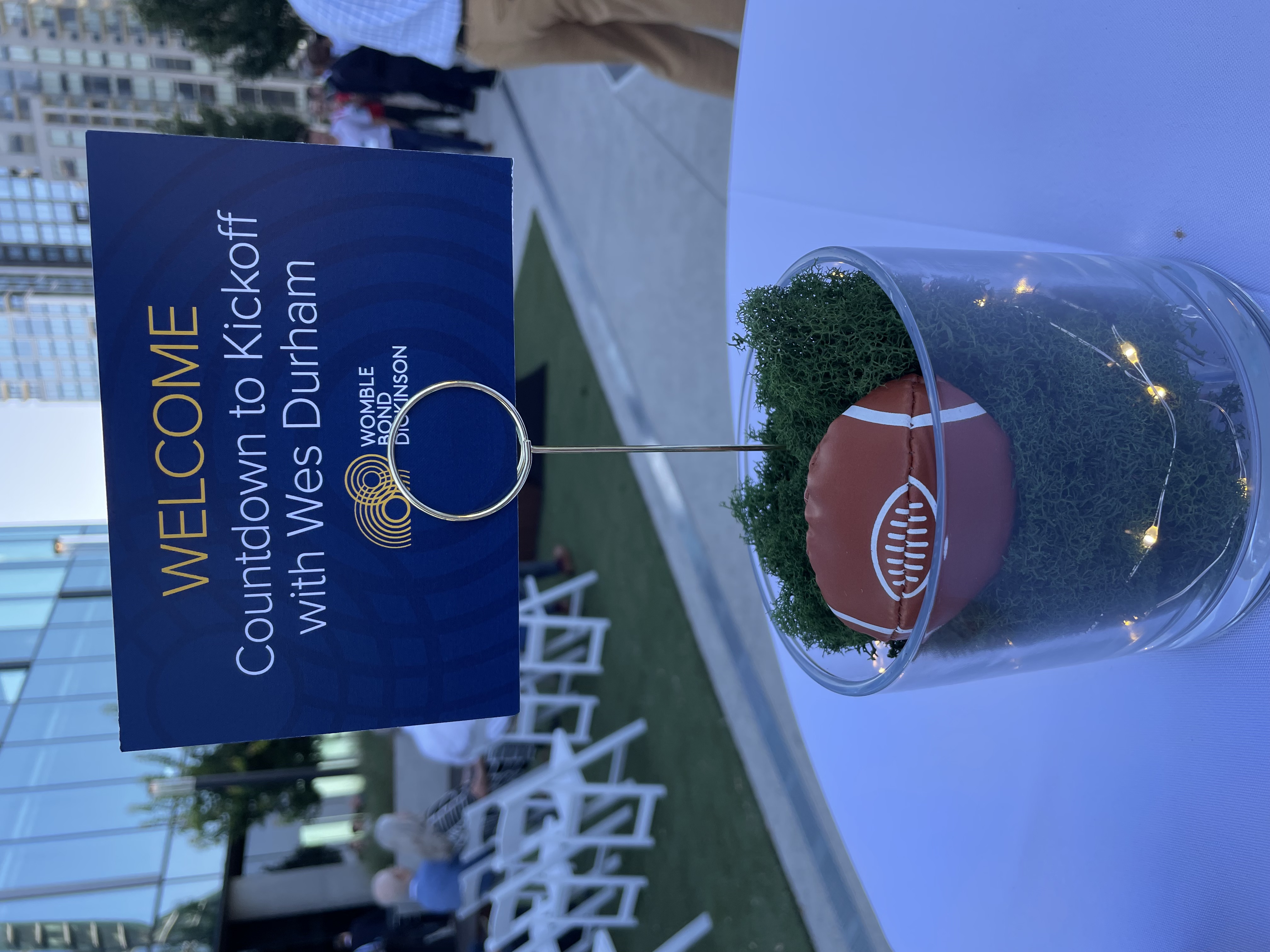 Table decoration with green mesh and a small football under a sign reading "Welcome: Countdown to Kickoff with Wes Durham"