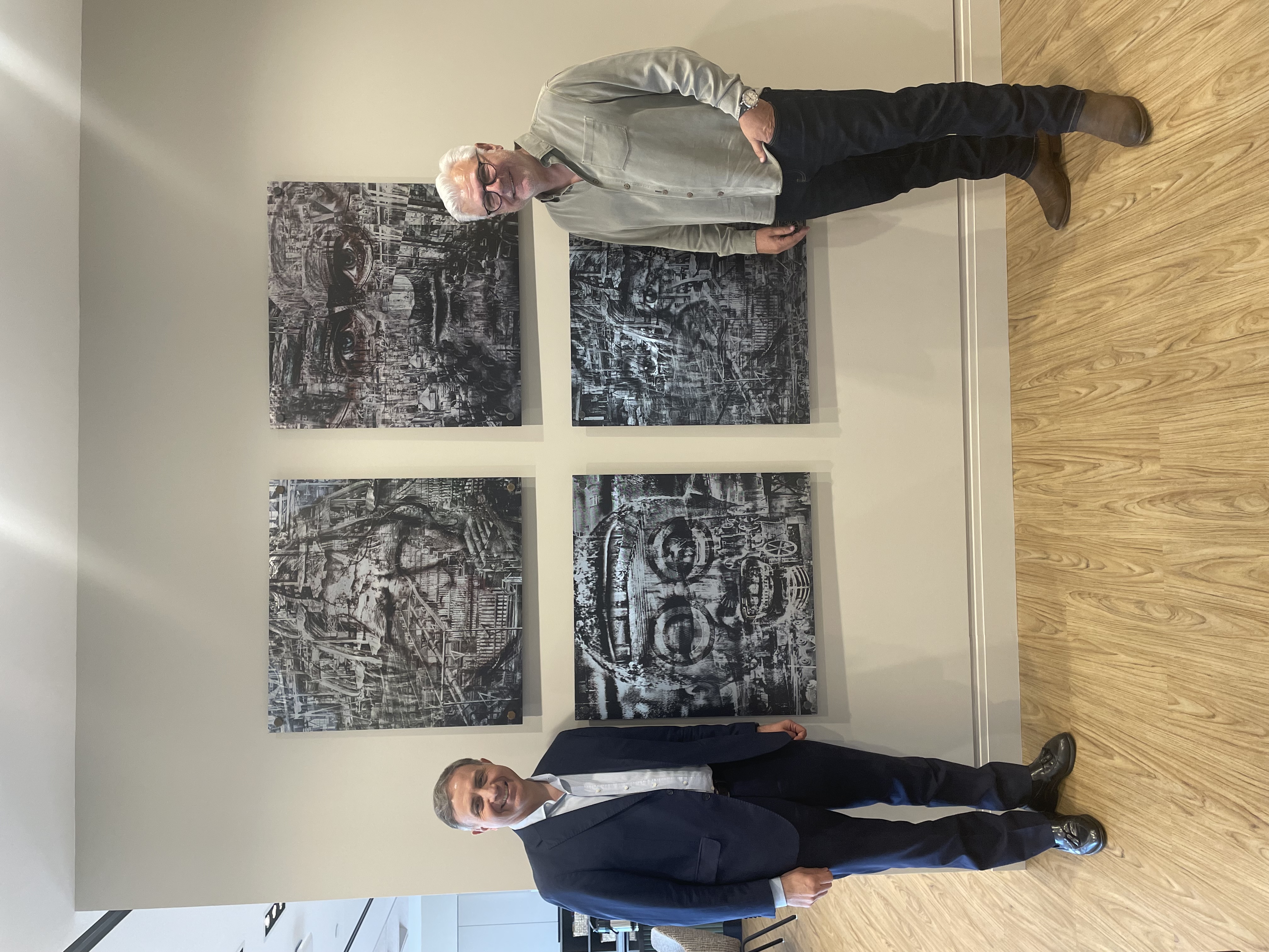 John Bernard and José Luis Vittor stand in front of John's artwork titled Displaced.