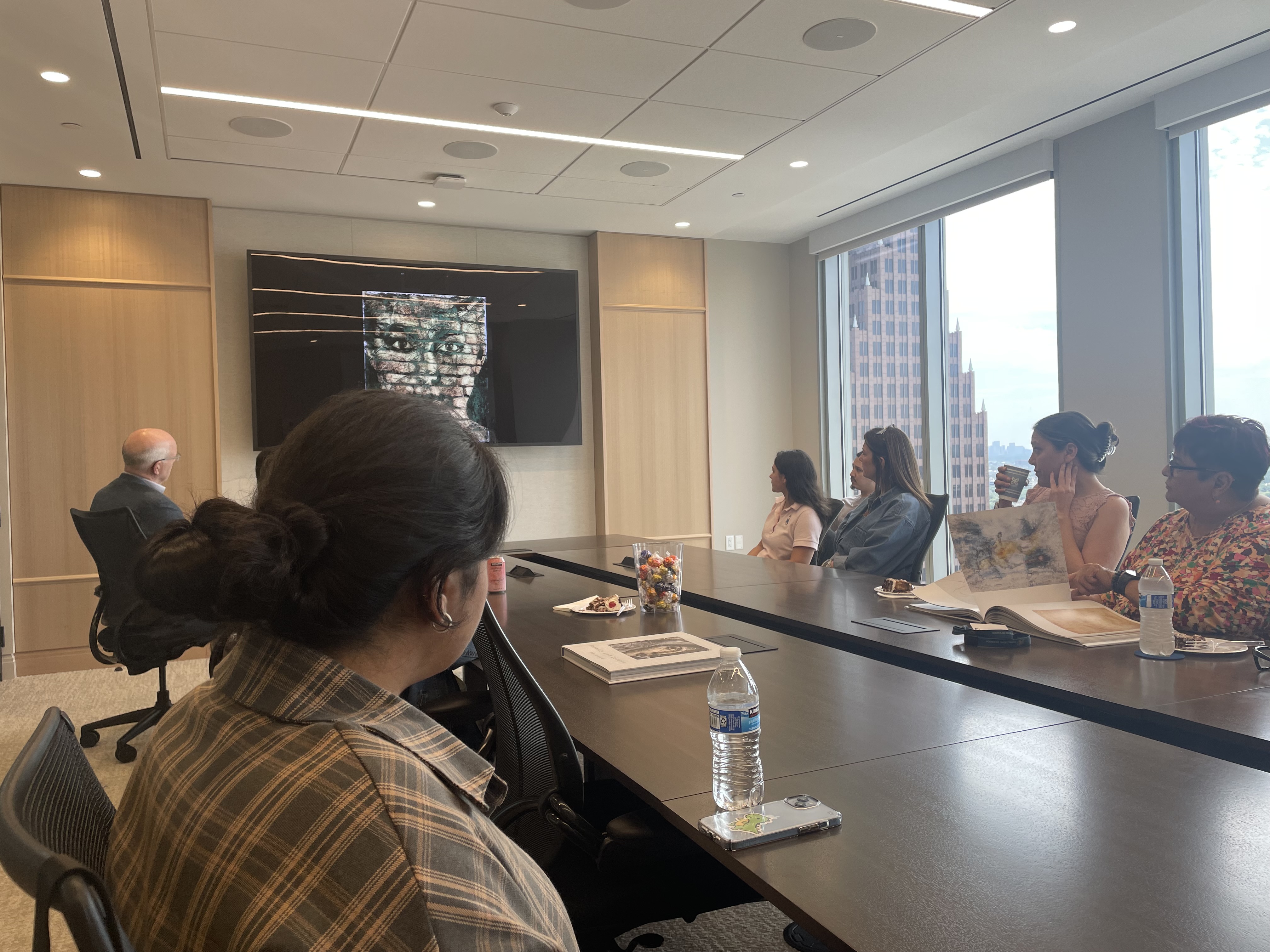 John Bernard speaks on a work of art displayed on a screen as members of our Houston office look on