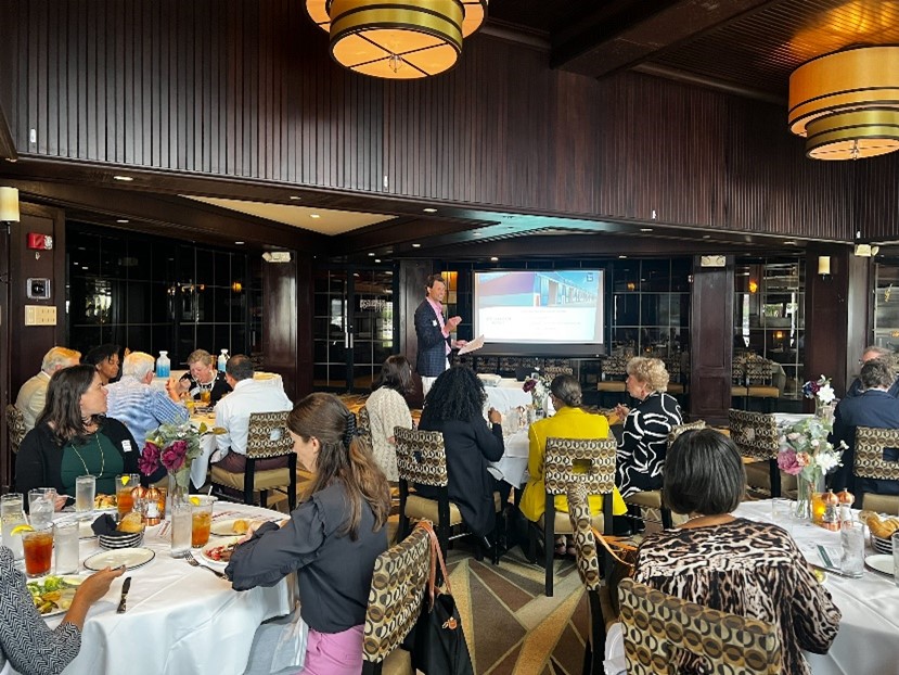 Keither Hinder presents to ACC Baltimore as attendees enjoy lunch at several tables.