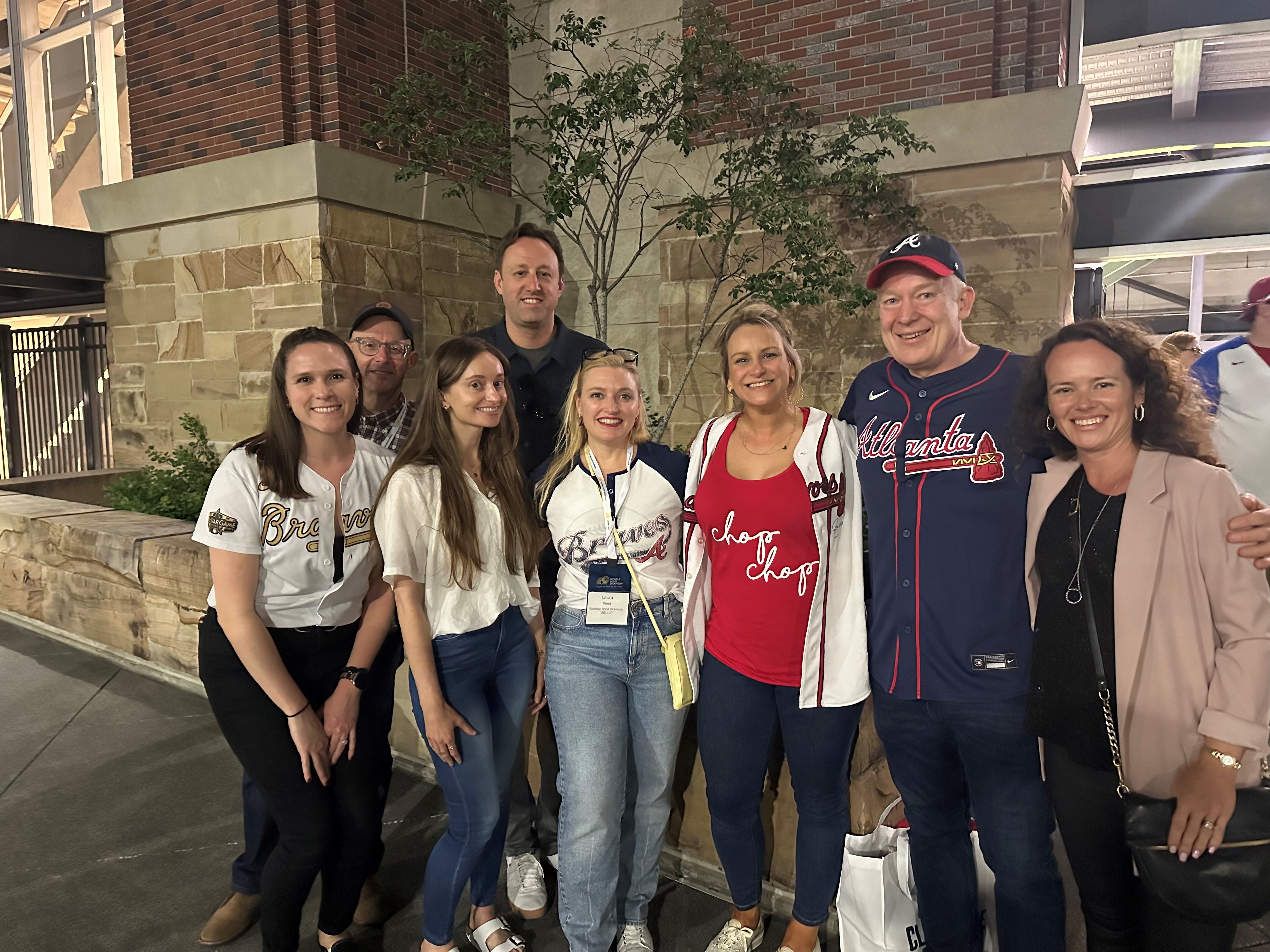 Our Womble IP team stands outside the Atlanta Braves stadium in Braves attire.