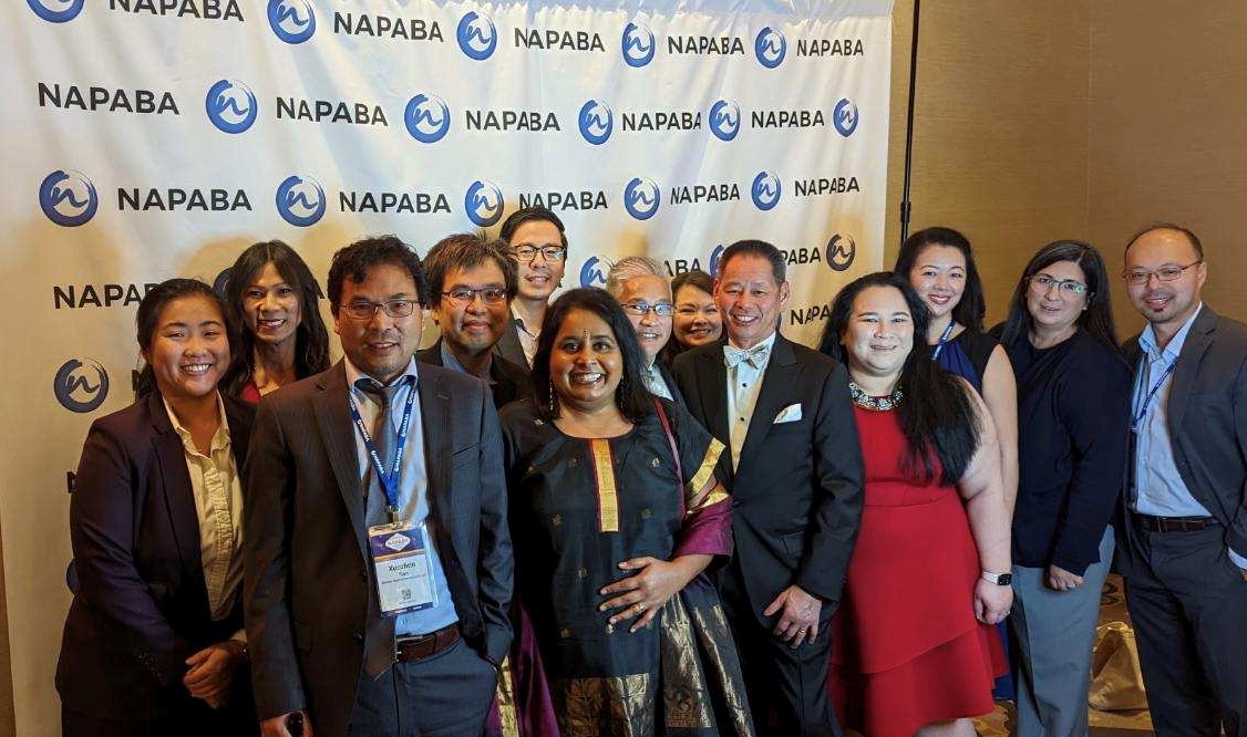 Womble Bond Dickinson attorneys stand in front of a NAPABA banner.