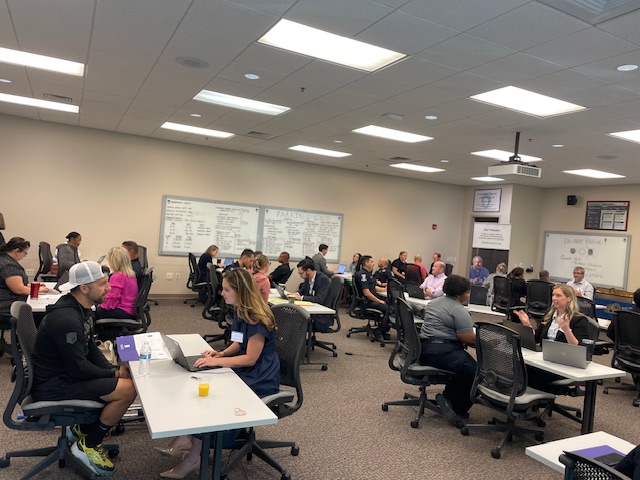 Attorneys work to provide free legal services to first responders sitting at tables in a large room.