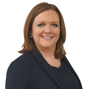 Professional woman in business attire with confident smile against white background.