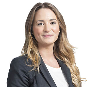 Professional woman in business attire smiling against a white background.