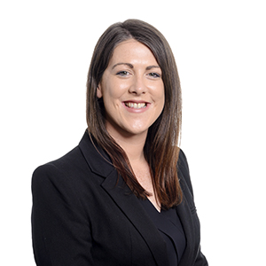 Professional woman in business attire with confident smile against white background.