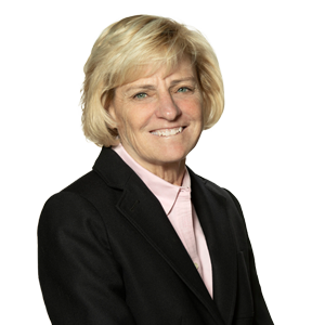 Professional woman with blond hair smiling, wearing a black blazer and pink shirt, corporate business attire, isolated on a white background.