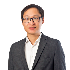 Professional Asian businessman wearing glasses and a dark grey suit with a white shirt, smiling confidently against a white background.