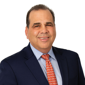 Professional man in business attire with a confident smile, wearing a navy blue suit jacket, white shirt, and a vibrant orange patterned tie.