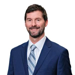 Professional man in business attire with a suit and tie smiling for a corporate headshot against a white background.