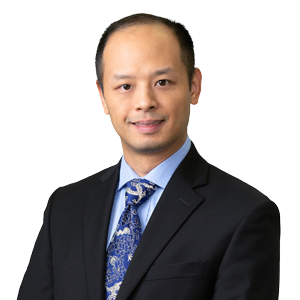Professional businessman wearing suit with blue tie and patterned shirt, posing for corporate headshot against a white background.