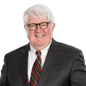 Cheerful senior businessman wearing spectacles, grey suit, and striped tie against a white background.