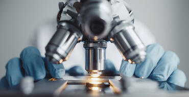 A scientist uses a microscope in a lab - Getty Images 911834392