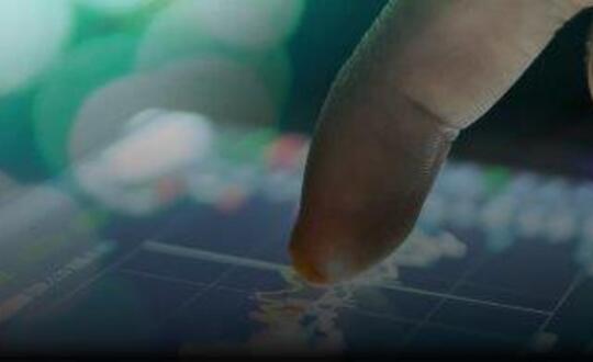 Close-up of a finger pointing at a touchscreen with digital graphs, symbolising data analysis and technological interaction in the finance sector.