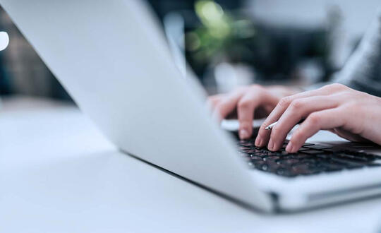Woman typing on computer - Getty Images 1132873727