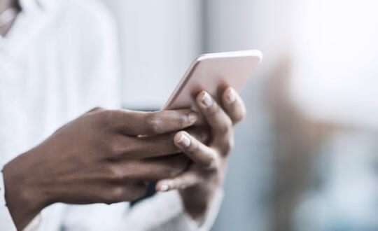 A businesswoman holds a pink cell phone - Getty Images 1079719138