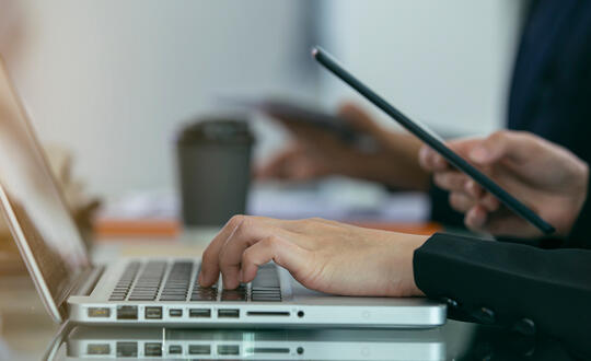 Business person using computer and phone - Shutterstock 1591884118