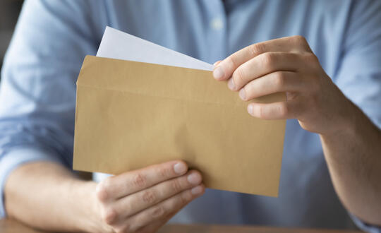 A man opens a letter from a blank envelope - Shutterstock 1854695014