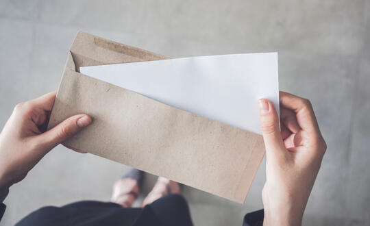 Businesswoman opening a letter - Shutterstock 1073014880