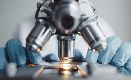 A scientist uses a microscope in a lab - Getty Images 911834392