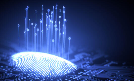 A thumbprint lights up on top of a print-reading surface, as data is gathered and symbolized by ones and zeros lifting up from the thumbprint.