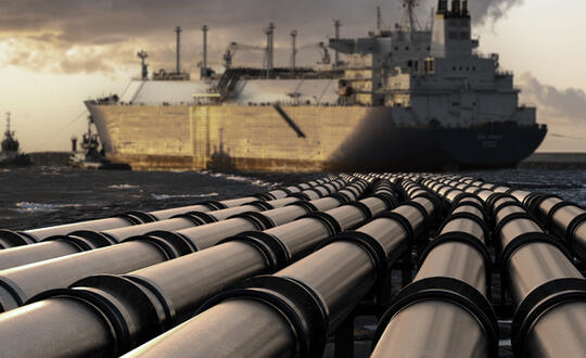 A tanker carrying liquified natural gas (LNG)  cruises behind several pipes also containing liquified natural gas.