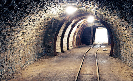 A coal mine leads out into sunlight - Shutterstock 293613770
