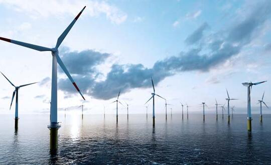 Offshore wind farm during sunrise with multiple turbines and calm sea, showcasing renewable energy sources and sustainable electricity generation in the UK.