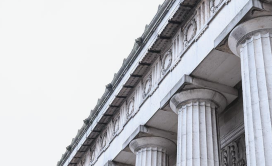 Classic Greco-Roman architecture with Corinthian columns in overcast British weather.