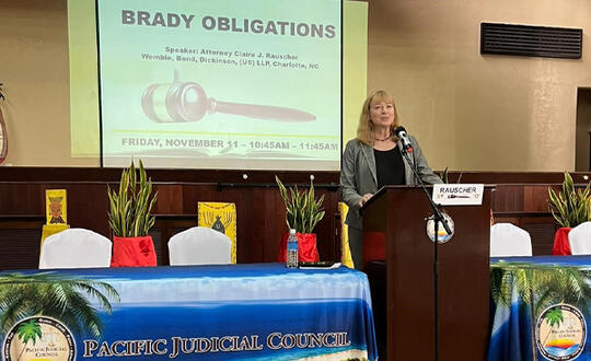 Womble Bond Dickinson Partner Claire Rauscher speaks at a podium, beside a banner that reads: "Pacific Judicial Conference".