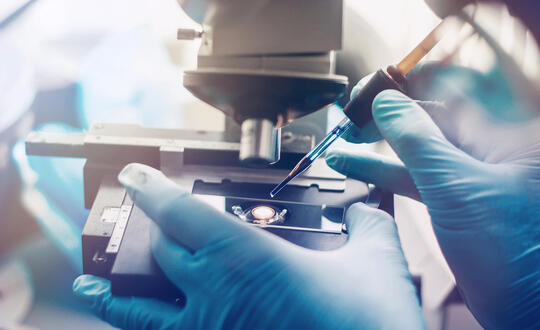 A lab technician using a microscope