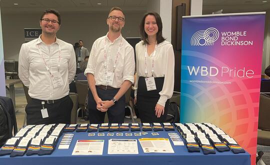 Womble attorneys Christos Christodoulou, James Clark, and Caitlin Augerson at the WBD Pride display during Lavender Law 2024.