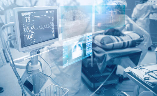 Screens and futuristic holograms with patient health data beside healthcare providers and a patient's bed.