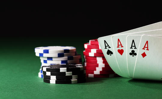 Playing cards with all suits of ace and a pile of chips on a green table