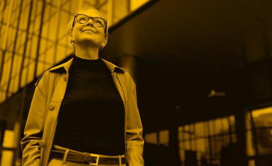 Woman wearing glasses looking up with corporate buildings in background