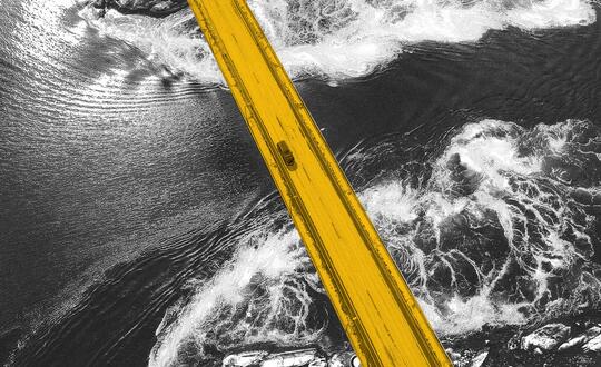 Bird's eye view of yellow bridge over black and white water