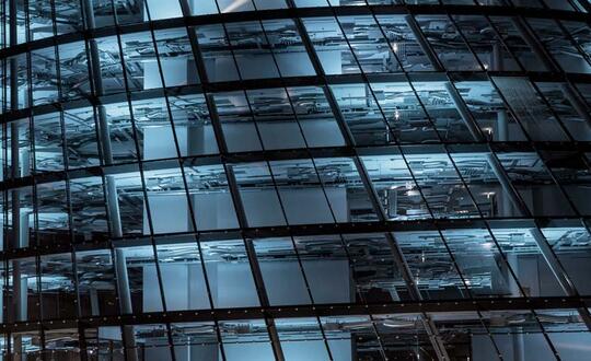 Close-up of a modern office building's exterior with geometric glass facade reflecting the evening sky in an urban setting.