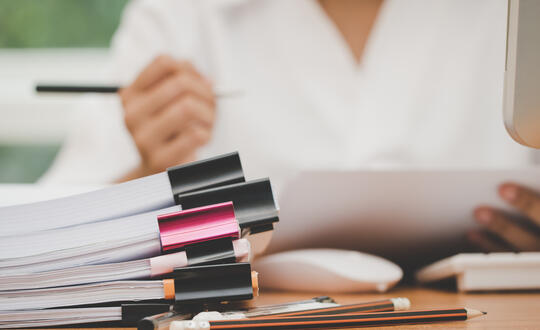 Woman working through pile of paperwork