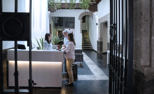 Guests checking in at a boutique hotel's reception desk with a welcoming interior, featuring minimalistic decor and natural lighting.