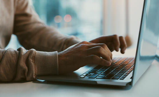 Person in sweatshirt typing on laptop