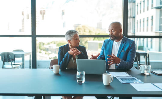Two people discussing business in a grey corporate office