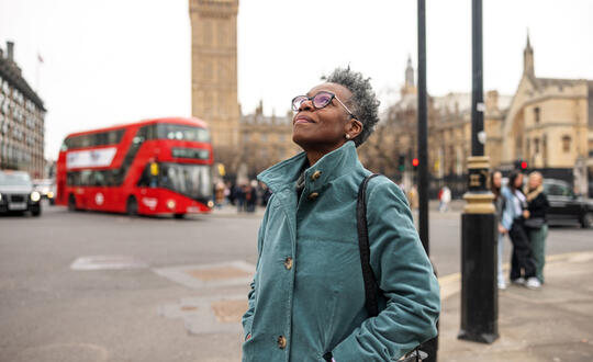 Elderly lady looking up at the sky in front on the House of Parliament