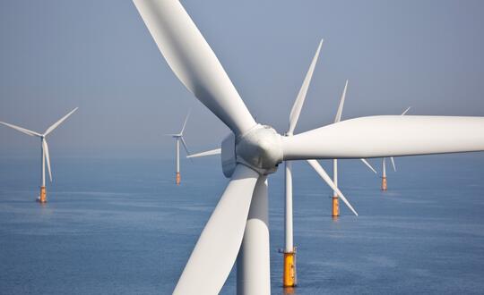 Close-up of offshore wind turbine with rotating blades in a wind farm at sea, sustainable energy generation, renewable resources, environmental conservation, modern technology in power industry.