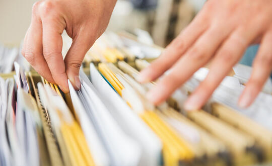 Person searching through files in filing cabinet