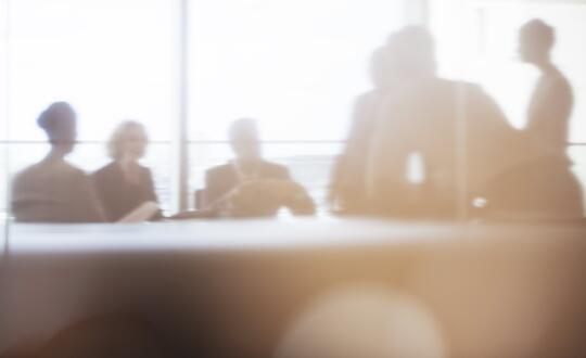 People in office meeting room through window, out of focus silhouettes
