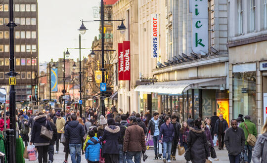 View of people walkign down a UK high street full of shops
