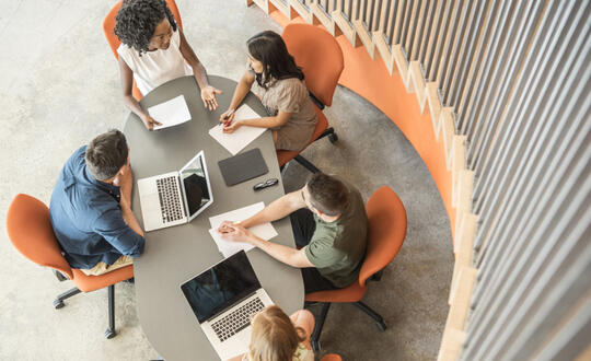 People sat on orange chairs working around a table