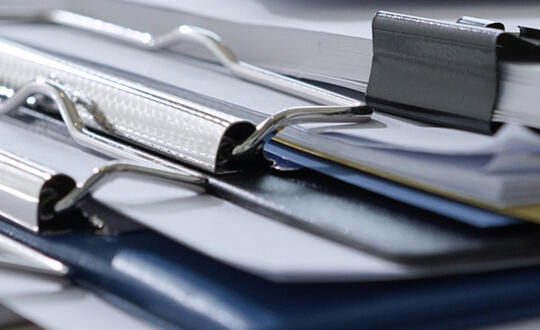 Close-up of assorted office ring binders on a desk, highlighting organisation, document storage, and filing efficiency.