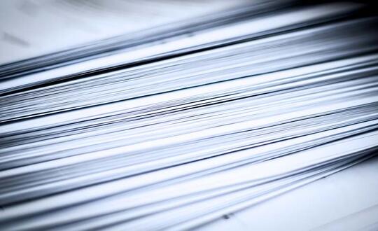 Close-up of stacked sheets of paper emphasising texture and pattern with cool blue tonal filter.