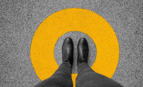 Downwards view of corporate feet in yellow circle